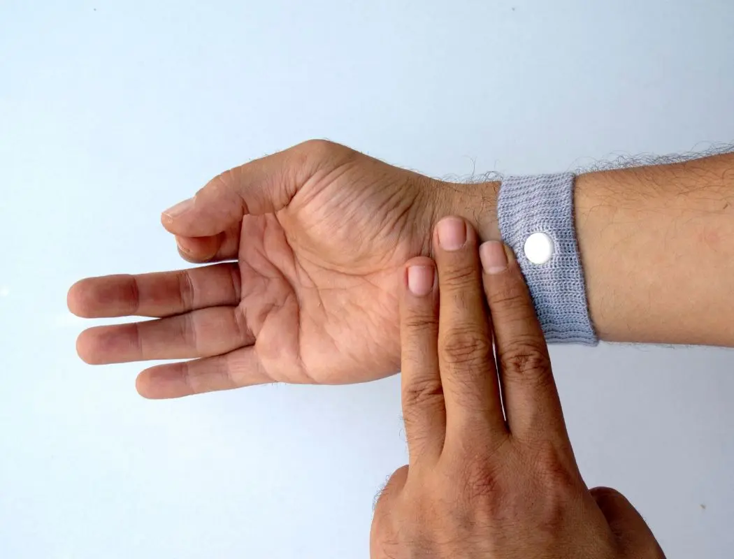 Man pressing wrist with three fingers while wearing anti-nausea wristbands
